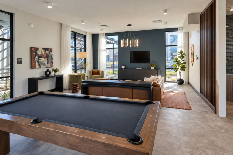 Bob Apartments’ modern lounge features a pool table, seating area, wall-mounted TV, large windows, and contemporary furnishings