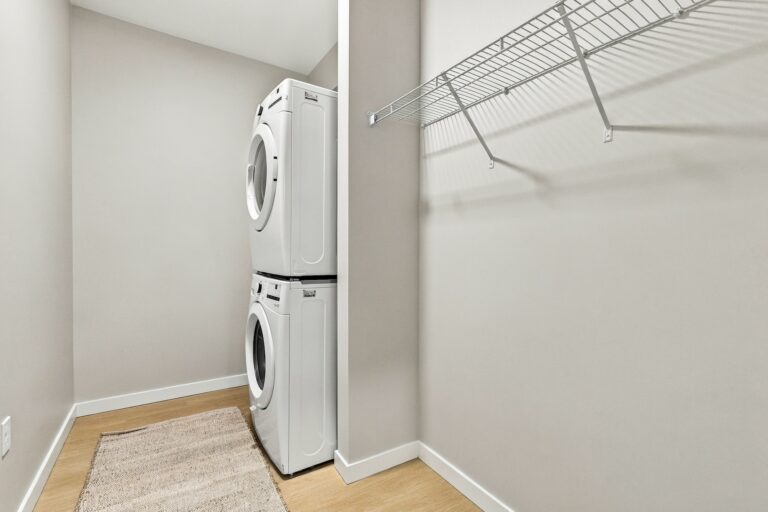In-unit laundry room at Bob Apartments with a stacked washer and dryer and wire shelving