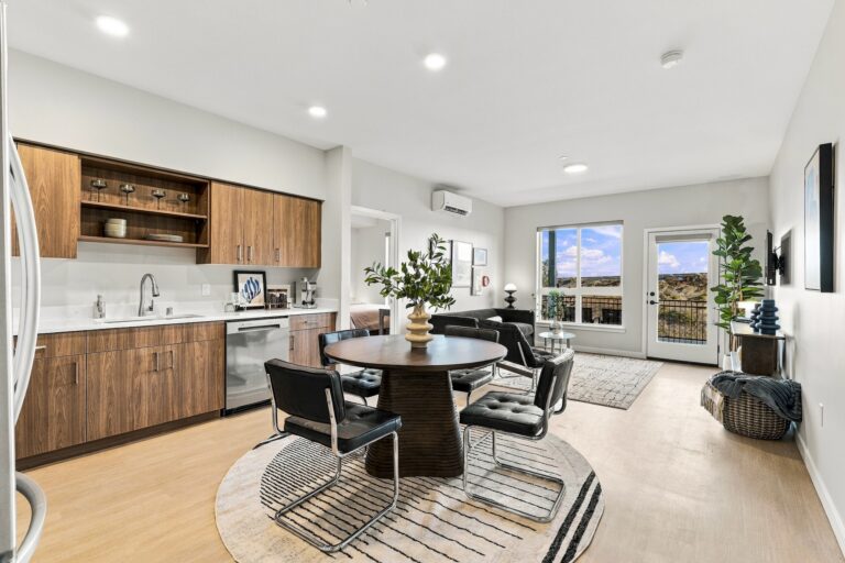 Open-plan Bob Apartments unit with a modern kitchen, dining area, living room, and balcony overlooking a desert landscape