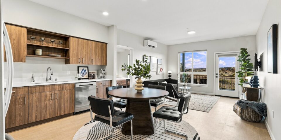 Open-plan Bob Apartments unit with a modern kitchen, dining area, living room, and balcony overlooking a desert landscape