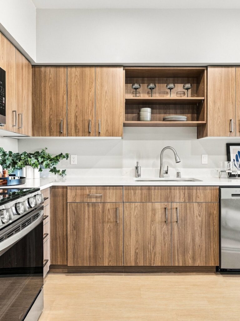 Modern Bob Apartments kitchen with wood cabinetry, stainless steel appliances, white countertops, and a sink