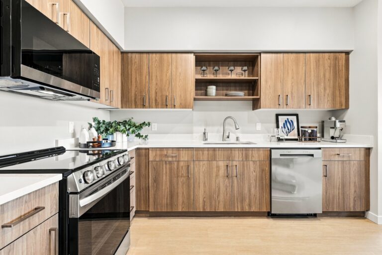 Modern Bob Apartments kitchen with wood cabinetry, stainless steel appliances, white countertops, and a sink